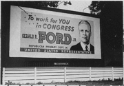 A billboard shows a portrait of a man in a suit, with the text