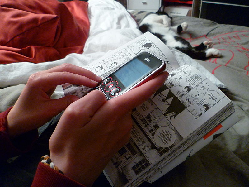 File:Teenage girl texting while reading a manga 1.jpg